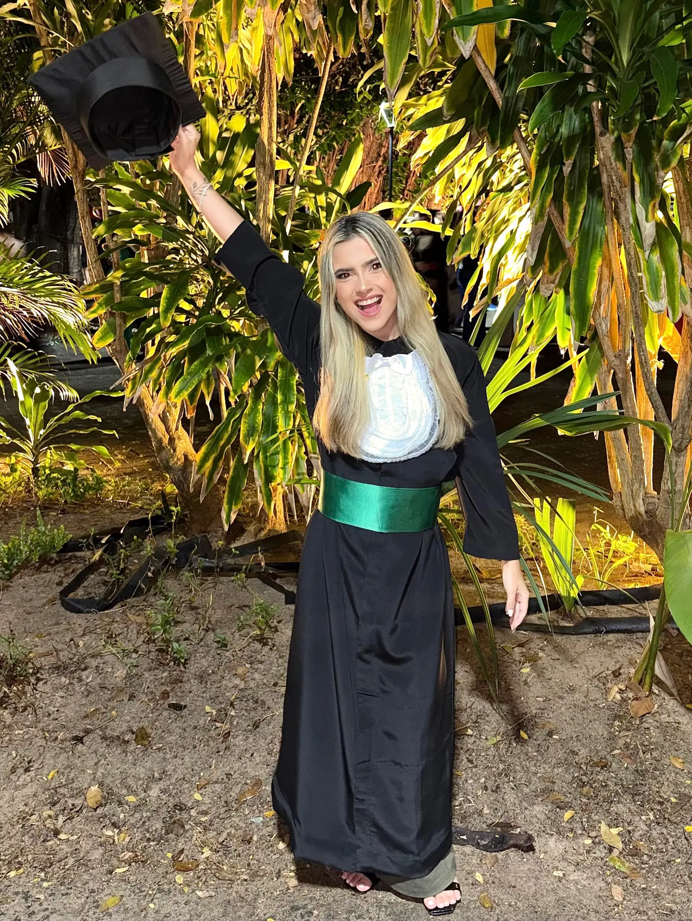 Sara Evangelista na formatura em Psicologia, de beca com faixa verde